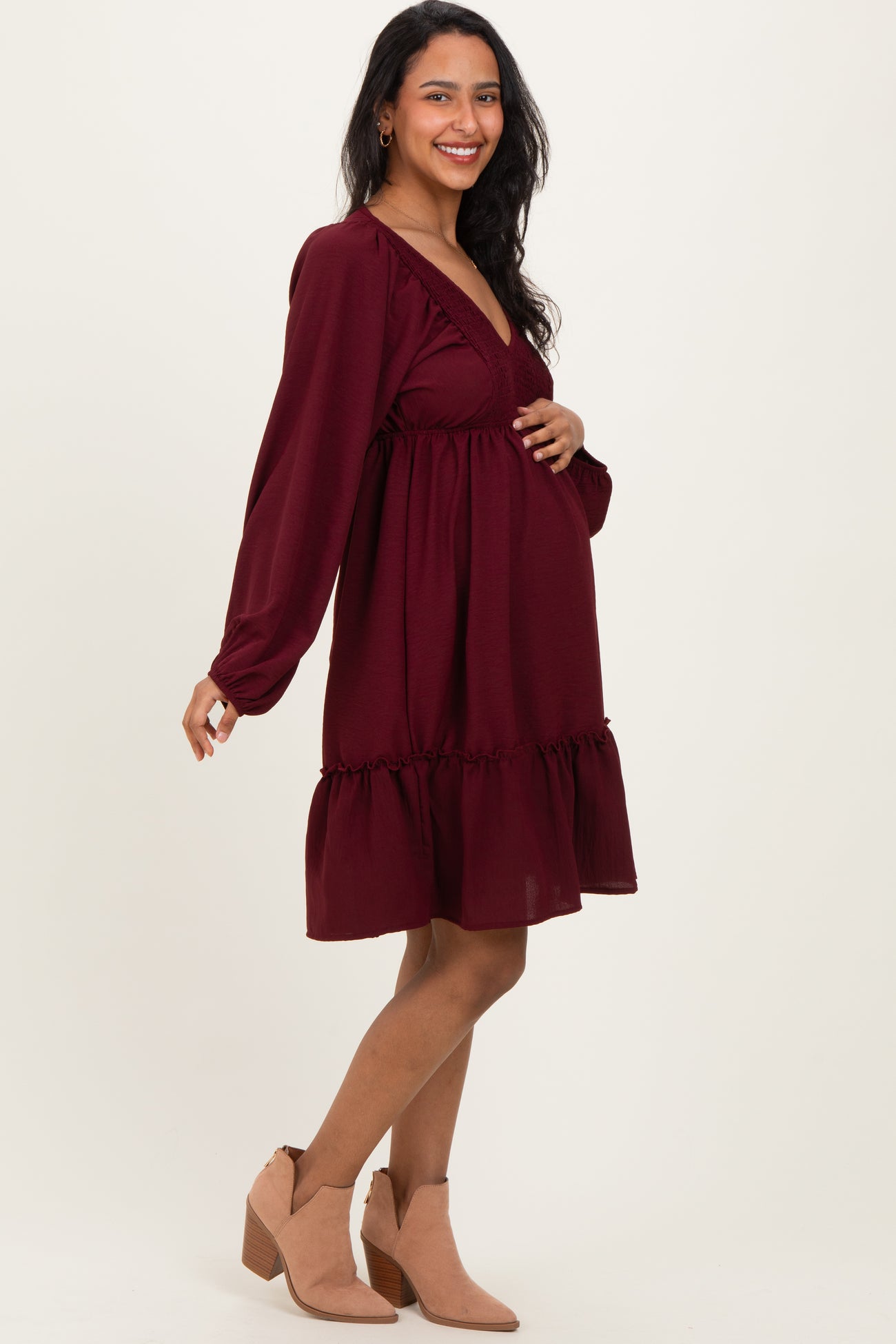 woman wearing a burgundy maternity dress with a ruffled hem and a v-neck, showing her baby bump
