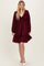 woman wearing a burgundy long sleeve smocked dress with a tiered skirt and deep v-neckline