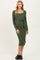 woman wearing a dark green long sleeve maternity dress with a square neckline and tie detail at the waist, showing her baby bump