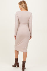 woman wearing a light taupe long sleeve fitted maternity dress, showing a sleek back view and knee-length style