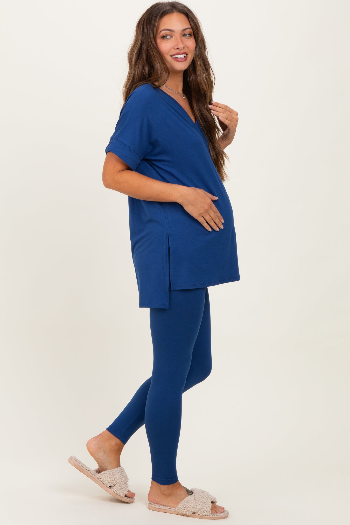 woman wearing a navy blue maternity top with side slits and matching leggings, highlighting her baby bump