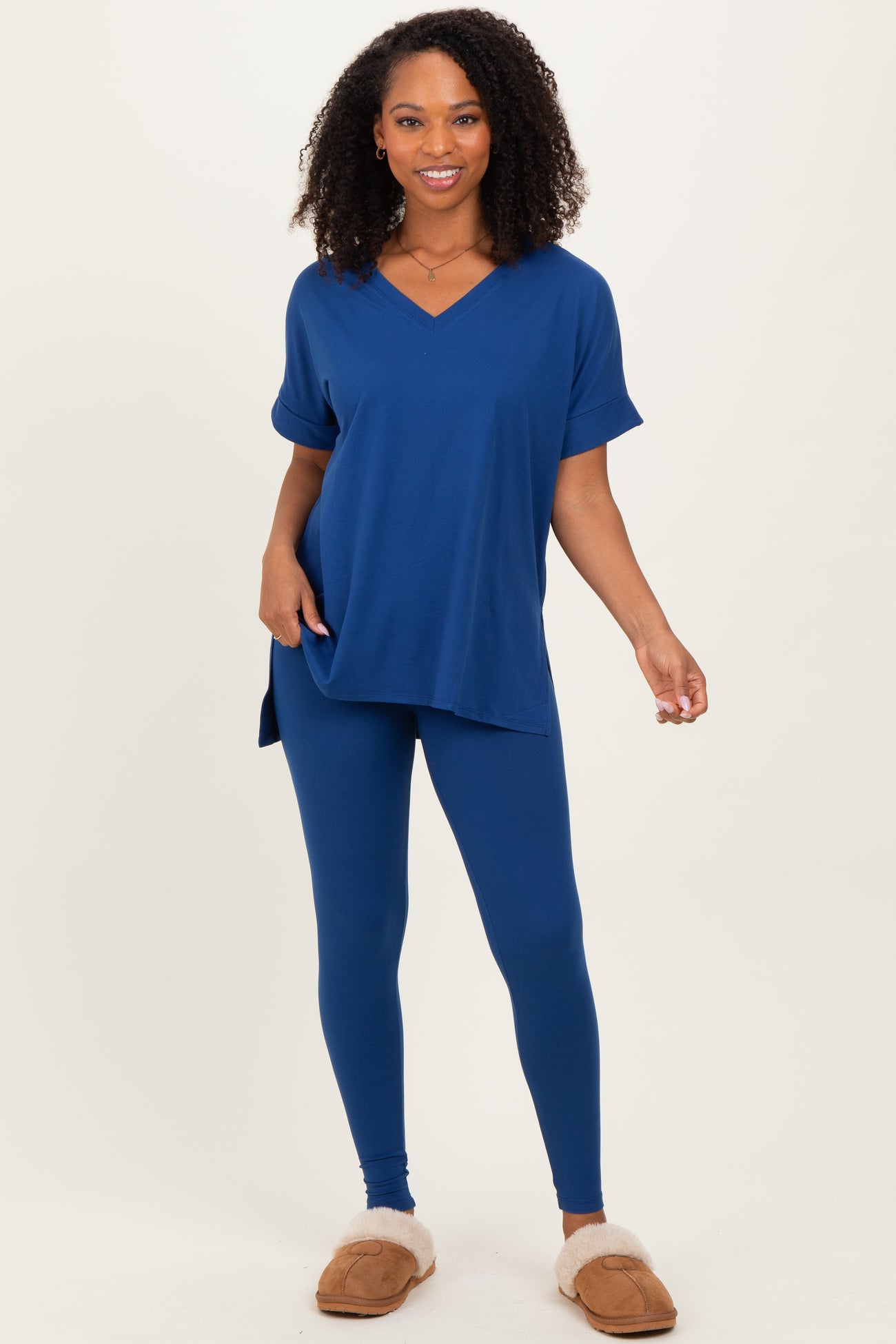 woman wearing a navy blue oversized v-neck tee and matching leggings, paired with tan slippers