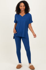 woman wearing a navy blue oversized v-neck tee and matching leggings, paired with tan slippers