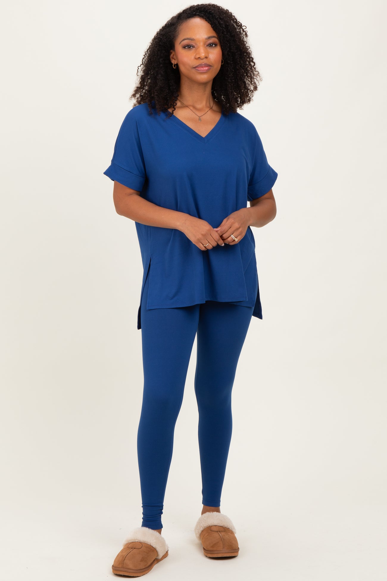 woman wearing a blue short sleeve v-neck top and matching blue leggings, styled with cozy slippers