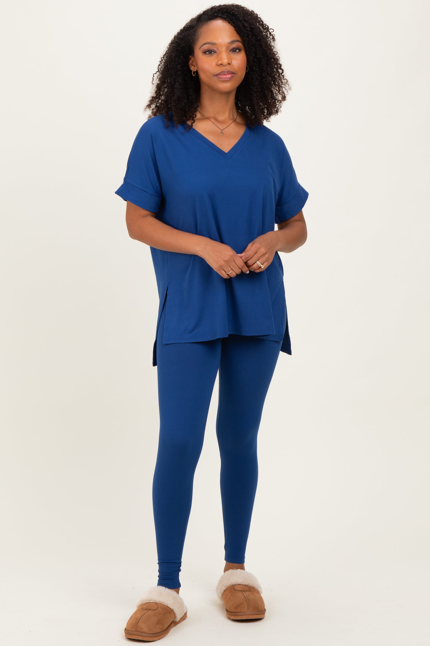 woman wearing a blue short sleeve v-neck top and matching blue leggings, styled with cozy slippers