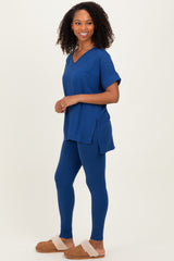 woman wearing a navy blue v-neck tunic top with side slits and matching leggings, styled with fuzzy slippers