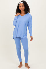 woman wearing a light blue long sleeve v-neck top and matching leggings, standing barefoot against a neutral background