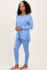 woman wearing a light blue long sleeve v-neck top and matching leggings, standing barefoot with a headband
