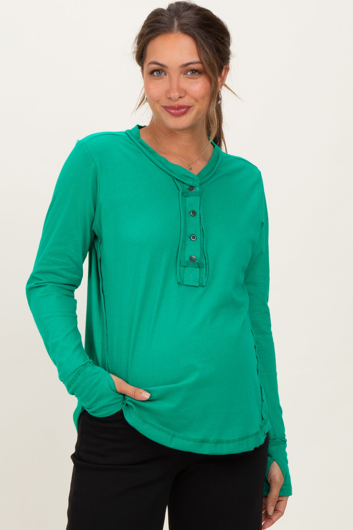 woman wearing a green long sleeve maternity top with buttons and a relaxed fit, showing her baby bump