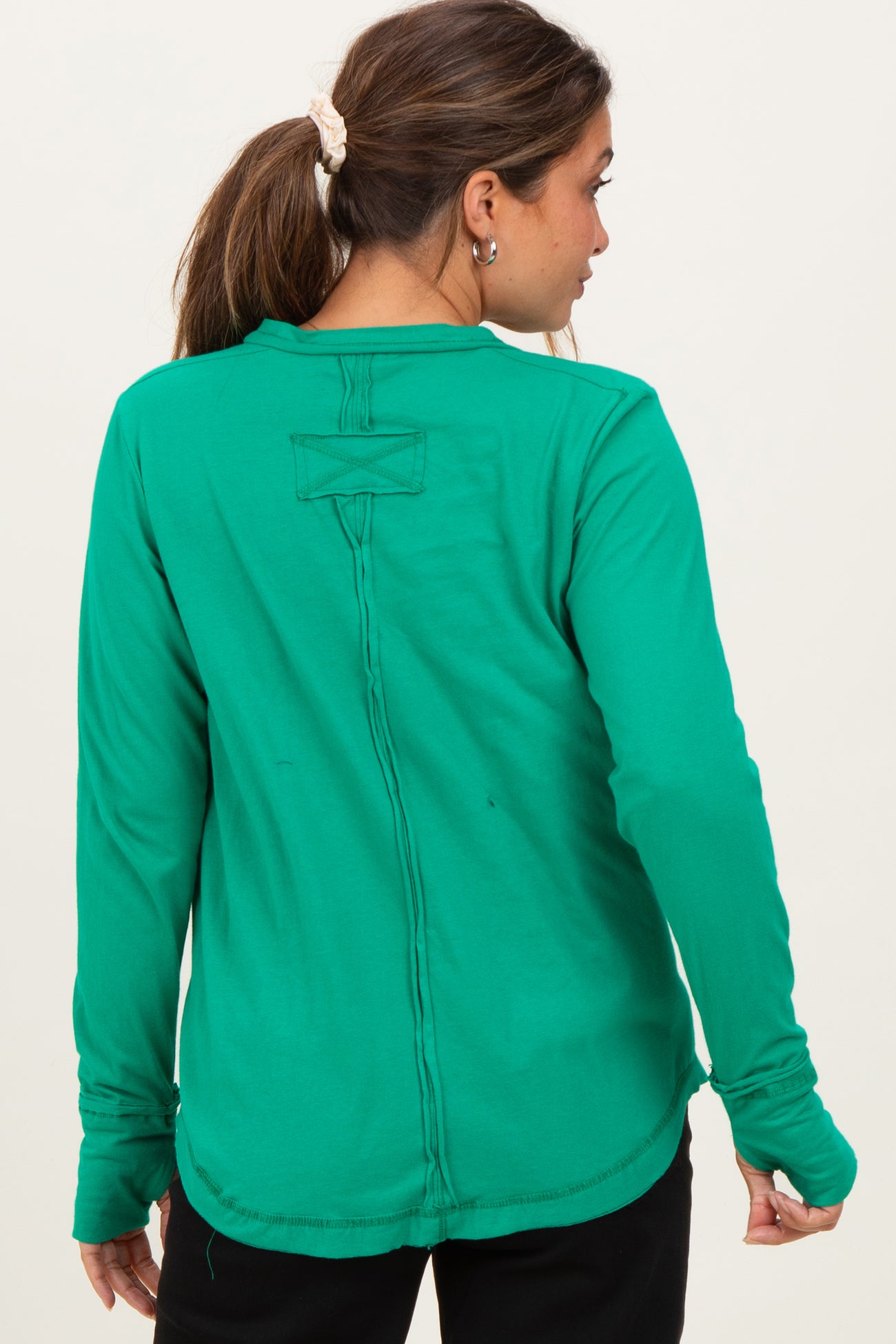 woman wearing a green long sleeve maternity top, showing a stylish back with stitched detail and relaxed fit