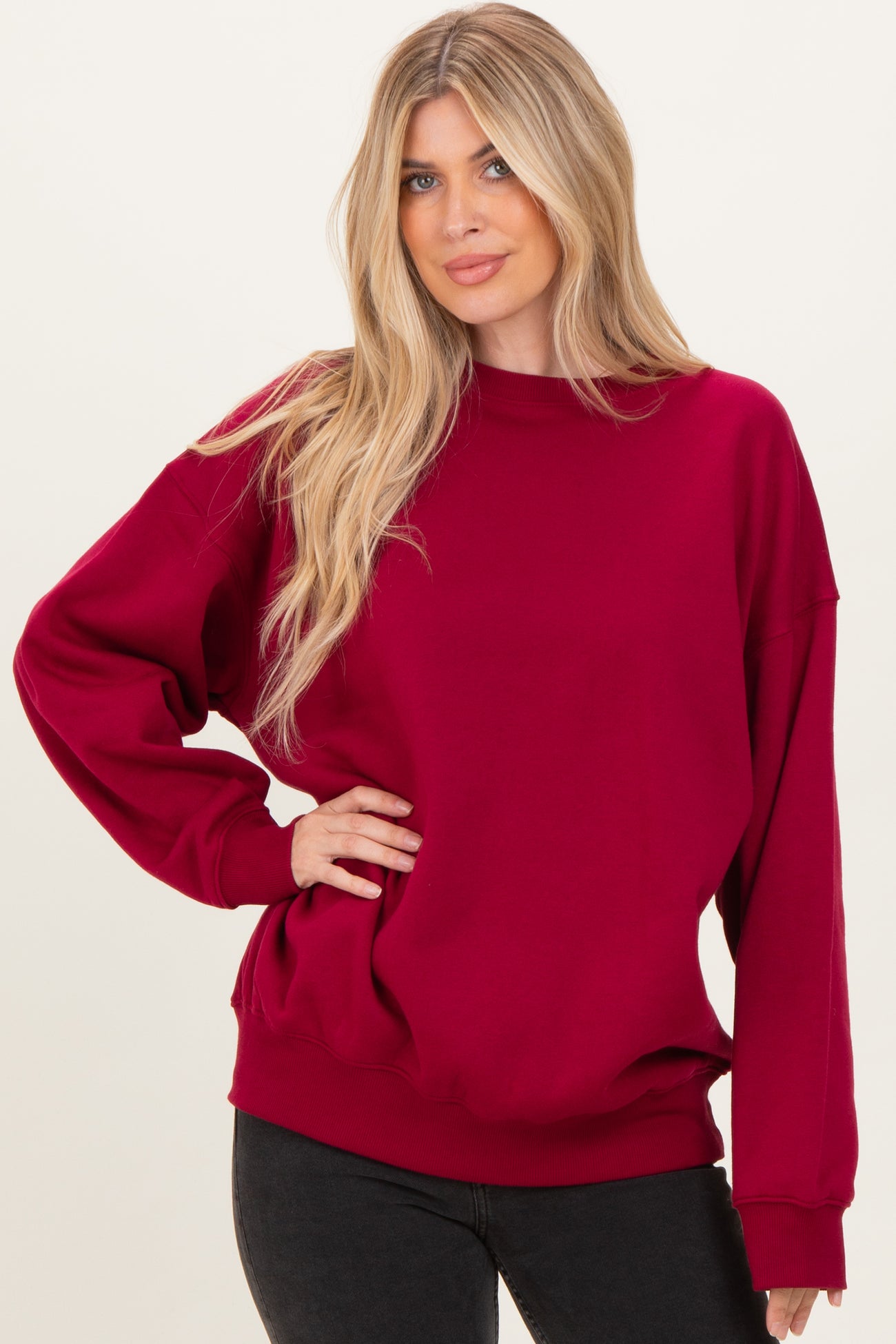 woman wearing a burgundy oversized sweatshirt with long sleeves and a crew neckline