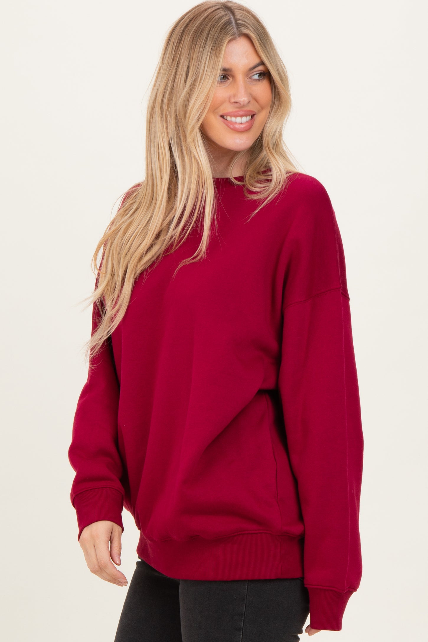 woman wearing a burgundy oversized sweatshirt with long sleeves and a relaxed fit