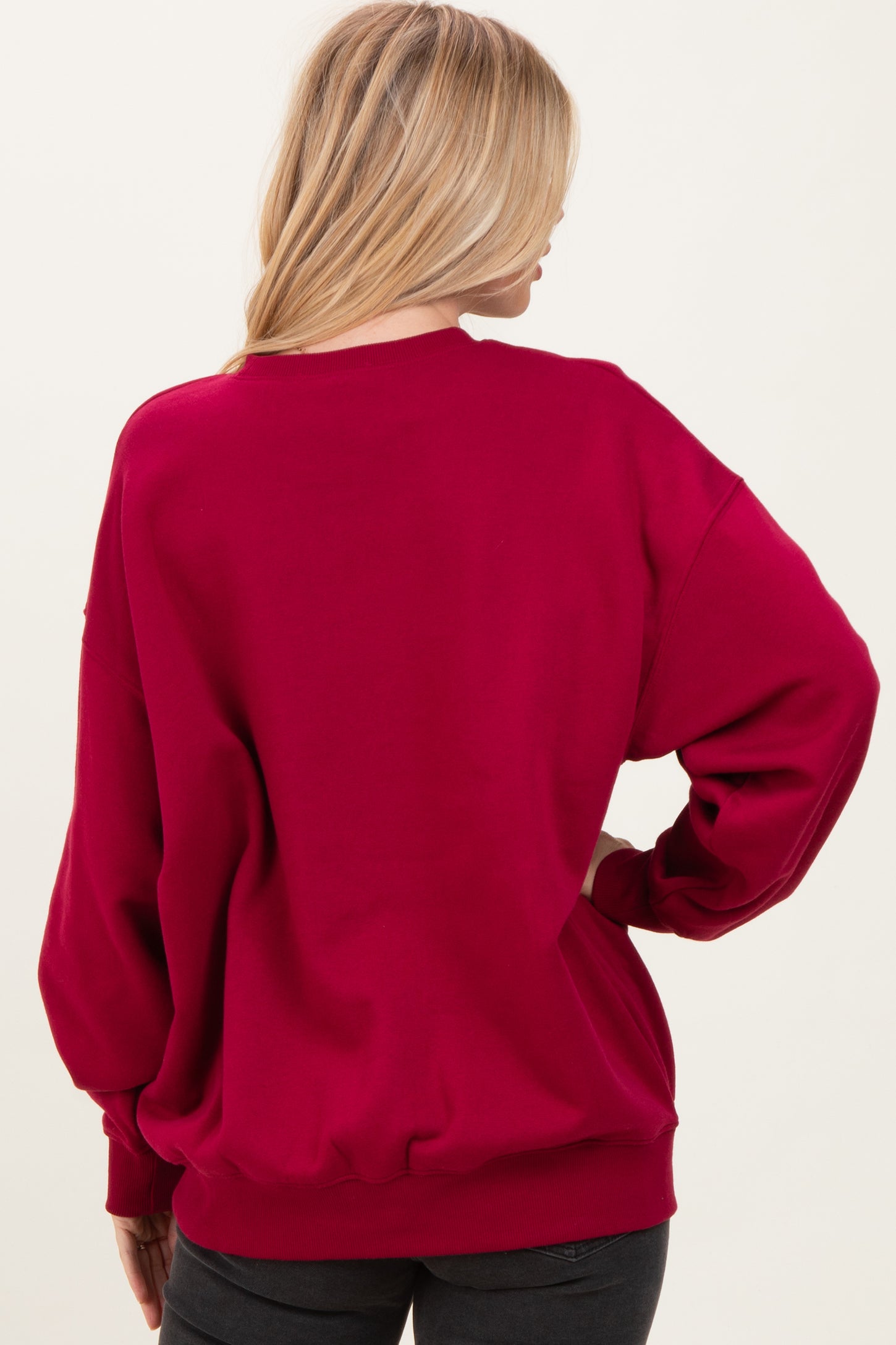 woman wearing a burgundy oversized sweatshirt with a relaxed fit and ribbed hem, viewed from the back