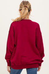 woman wearing a burgundy oversized maternity sweatshirt, view from the back