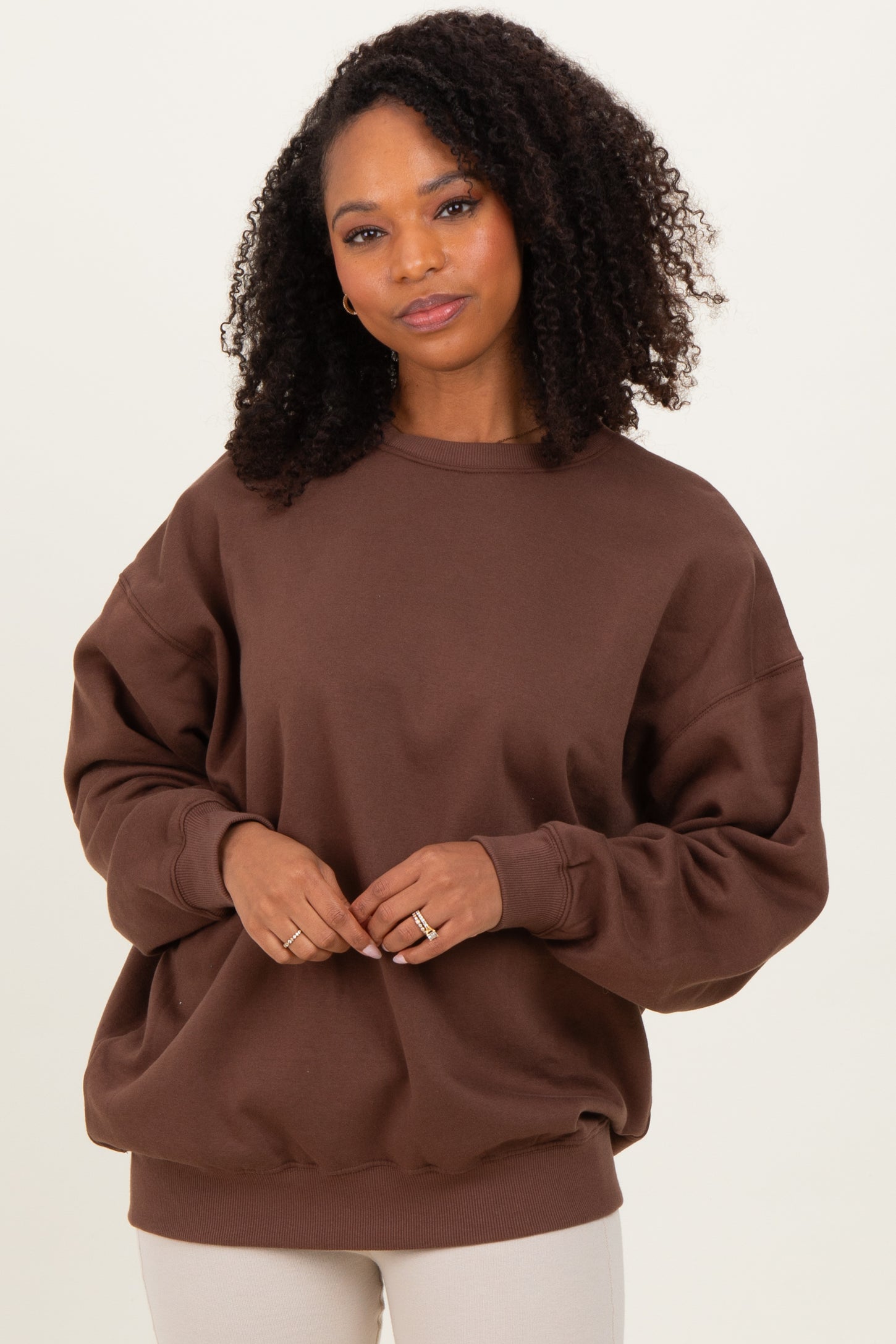 woman wearing a brown oversized sweatshirt with long sleeves and a relaxed fit