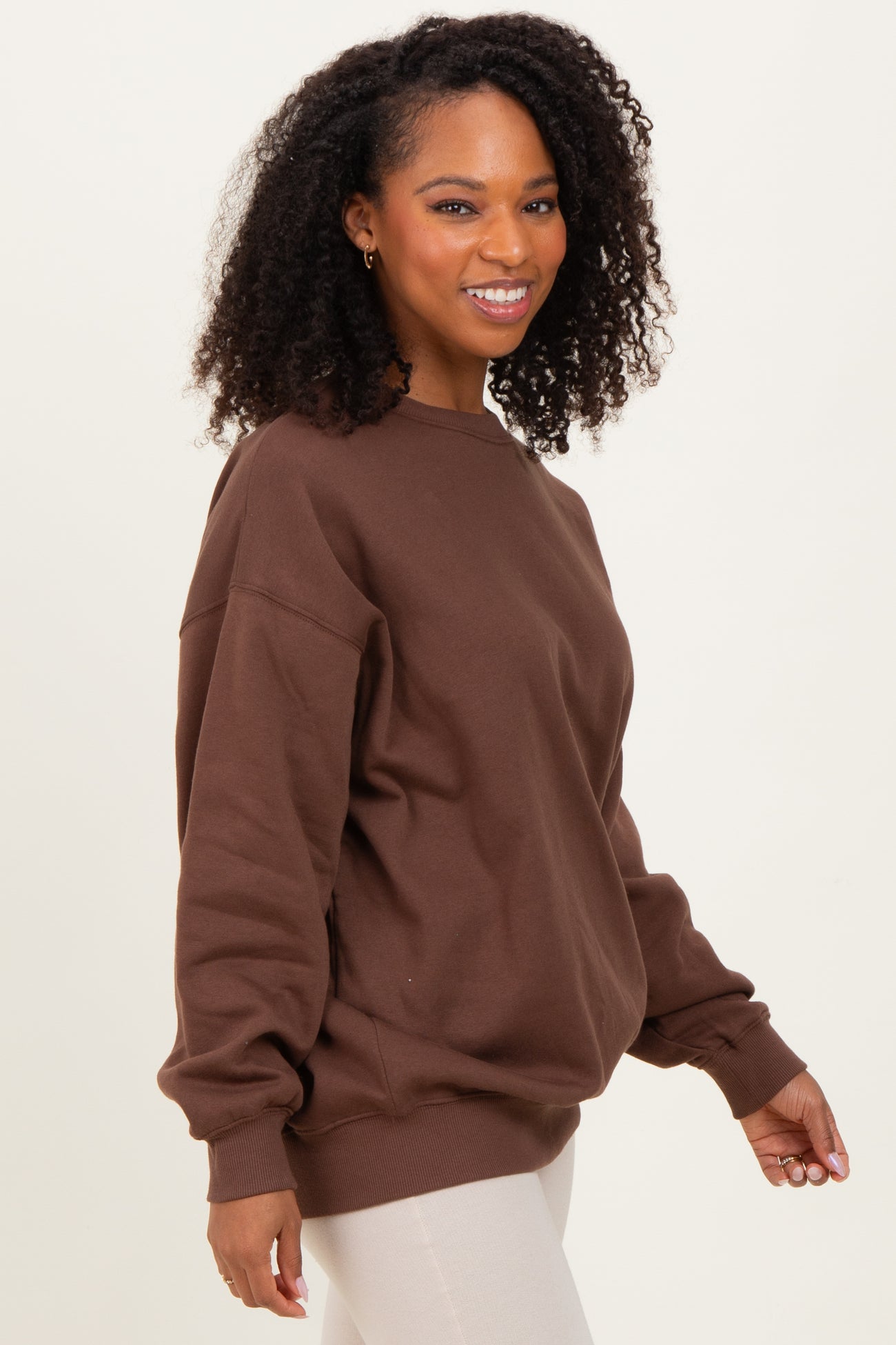 woman wearing a brown oversized sweatshirt with a crew neckline and relaxed fit