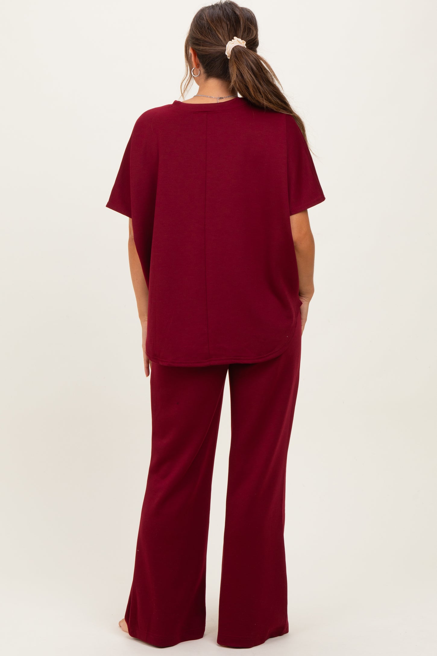 woman wearing a burgundy maternity top and matching flared pants, showing the back view of the outfit