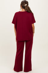 woman wearing a burgundy maternity top and matching flared pants, showing the back view of the outfit