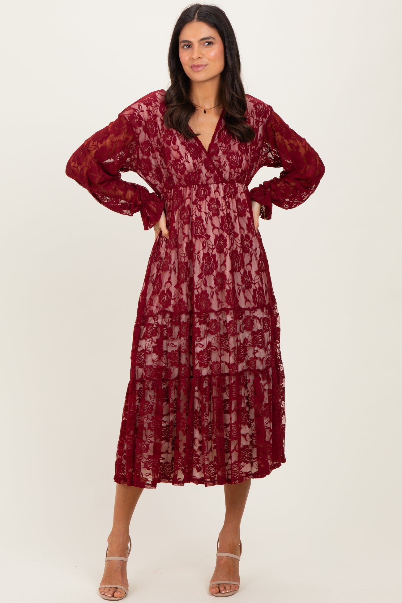 woman wearing a burgundy lace tiered maxi dress with long sleeves and a v-neckline