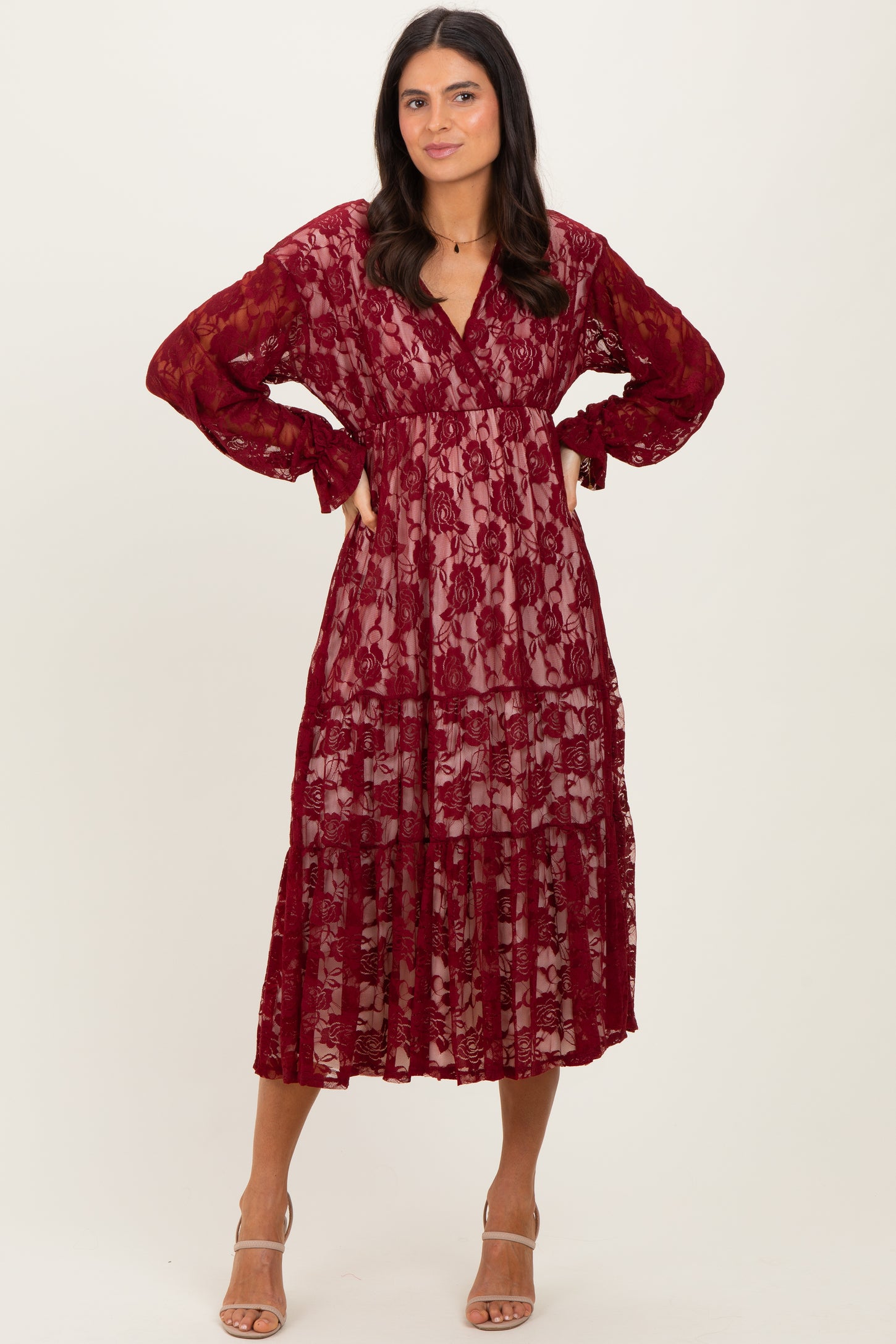 woman wearing a burgundy lace tiered maxi dress with long sleeves and a v-neckline