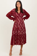 woman wearing a burgundy lace tiered maxi dress with long sleeves and a v-neckline