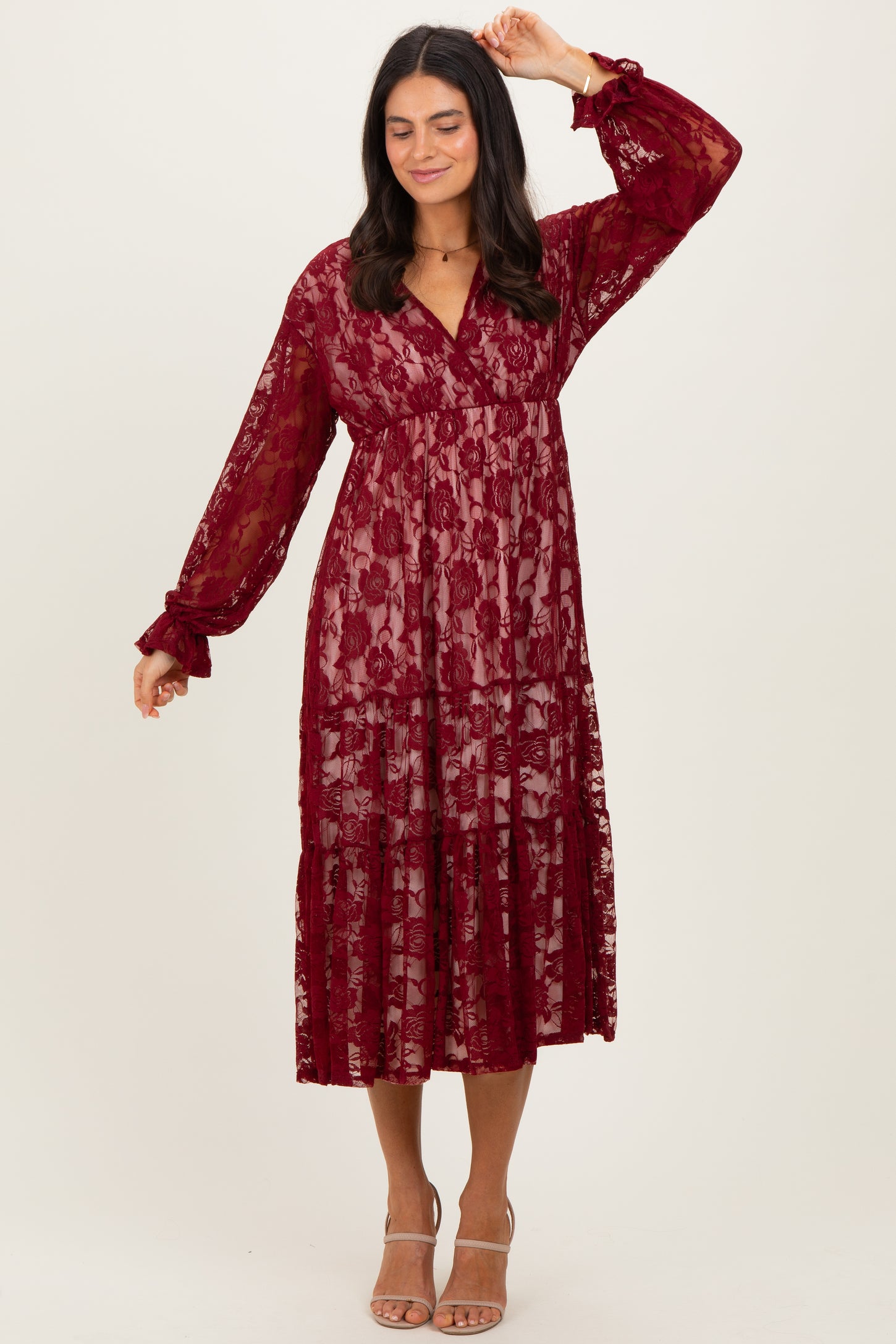 woman wearing a burgundy floral lace midi dress with long sleeves and tiered design