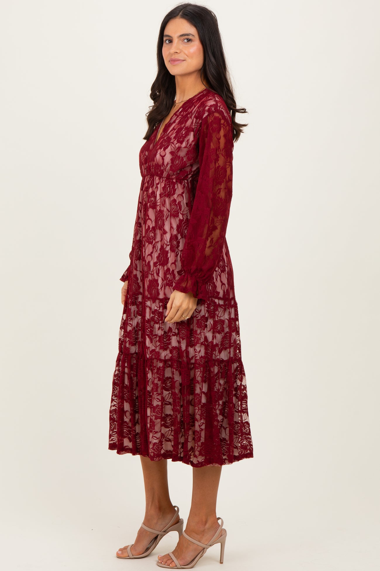 woman wearing a burgundy lace midi dress with long sleeves and a tiered skirt