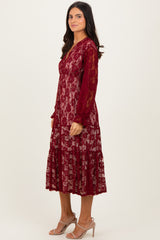 woman wearing a burgundy lace midi dress with long sleeves and a tiered skirt