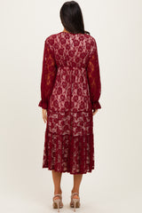 woman wearing a burgundy lace midi dress with long sleeves and a tiered skirt