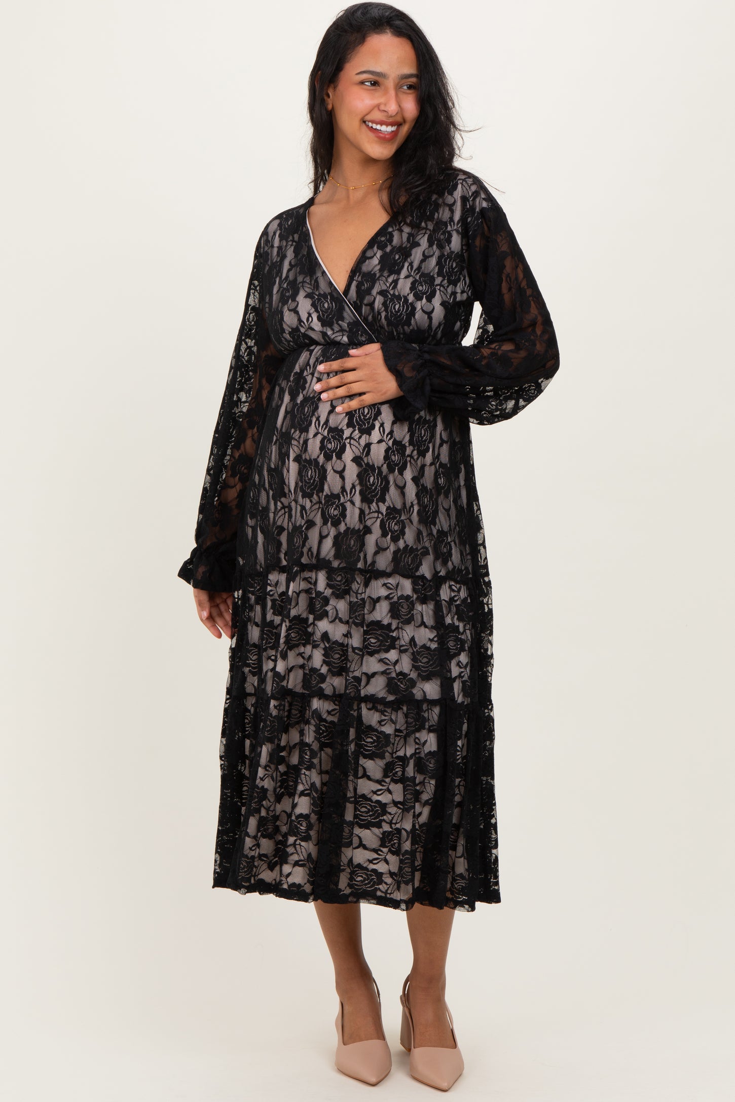woman wearing a black lace maternity dress with long sleeves and a flowy silhouette, showing her baby bump
