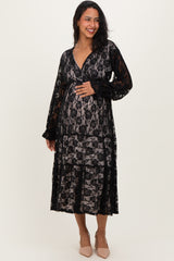 woman wearing a black lace maternity dress with long sleeves and a flowy silhouette, showing her baby bump