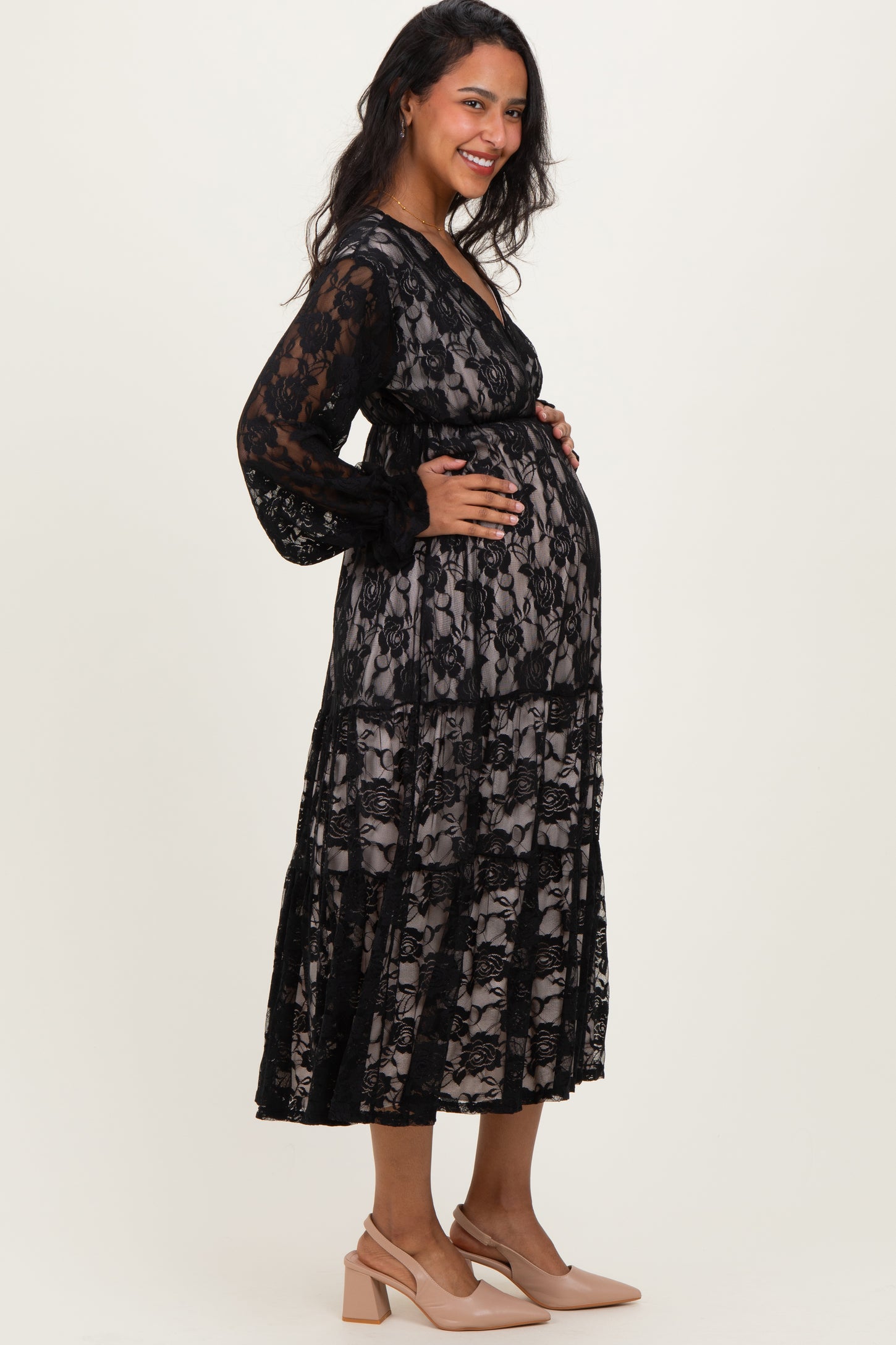 woman wearing a black lace maternity dress with a sheer overlay and a visible baby bump