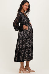 woman wearing a black lace maternity dress with a sheer overlay and a visible baby bump