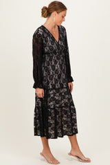 woman wearing a black lace midi dress with long sleeves and a layered skirt, styled with clear heeled sandals
