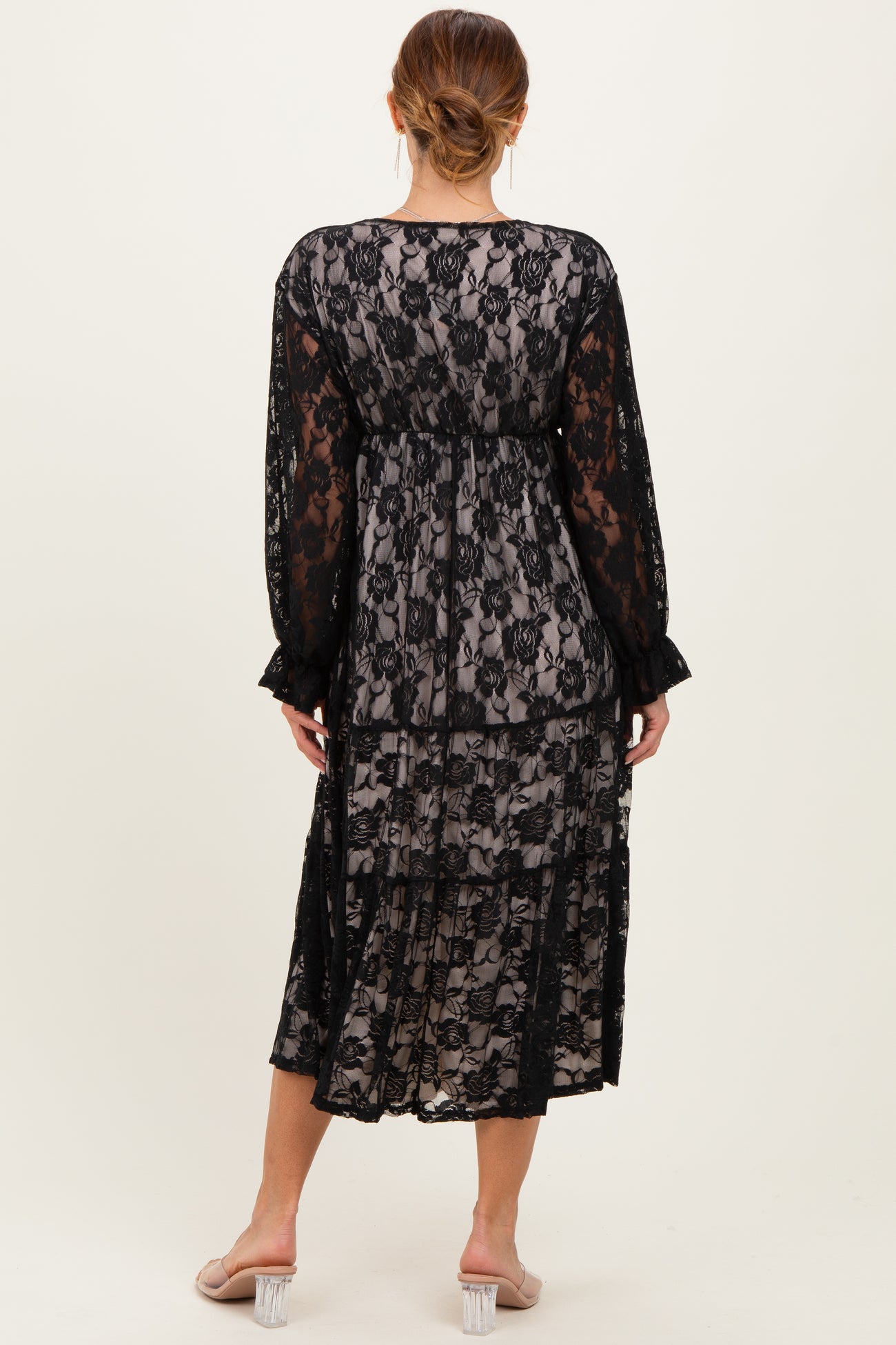 woman wearing a black lace maxi dress with long sleeves and tiered detailing, shown from the back