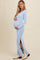 woman wearing a light blue ribbed maternity dress with side slits and holding her baby bump