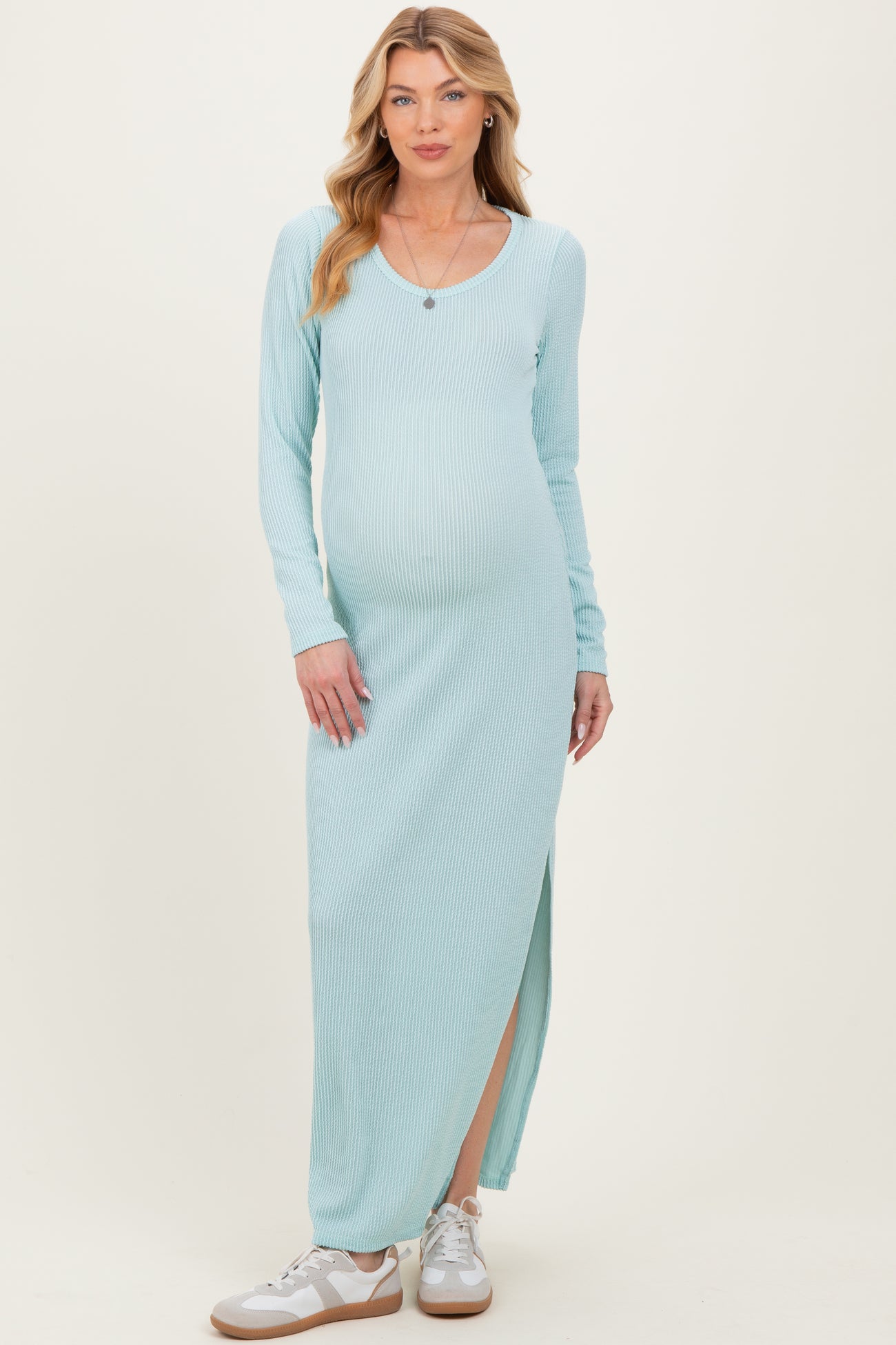 woman wearing a light blue long sleeve maternity maxi dress with a side slit and a visible baby bump