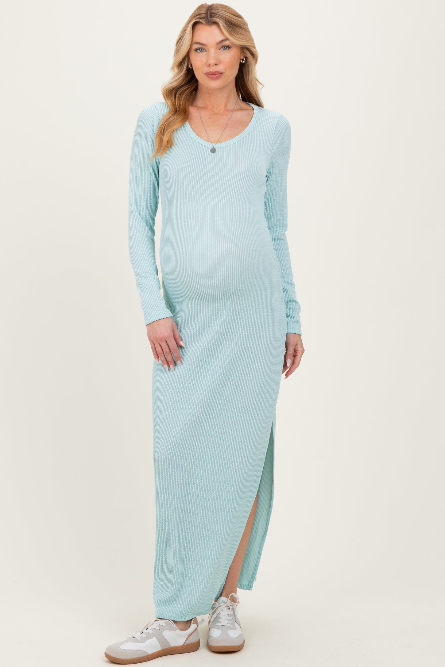 woman wearing a light blue long sleeve maternity maxi dress with a side slit and a visible baby bump