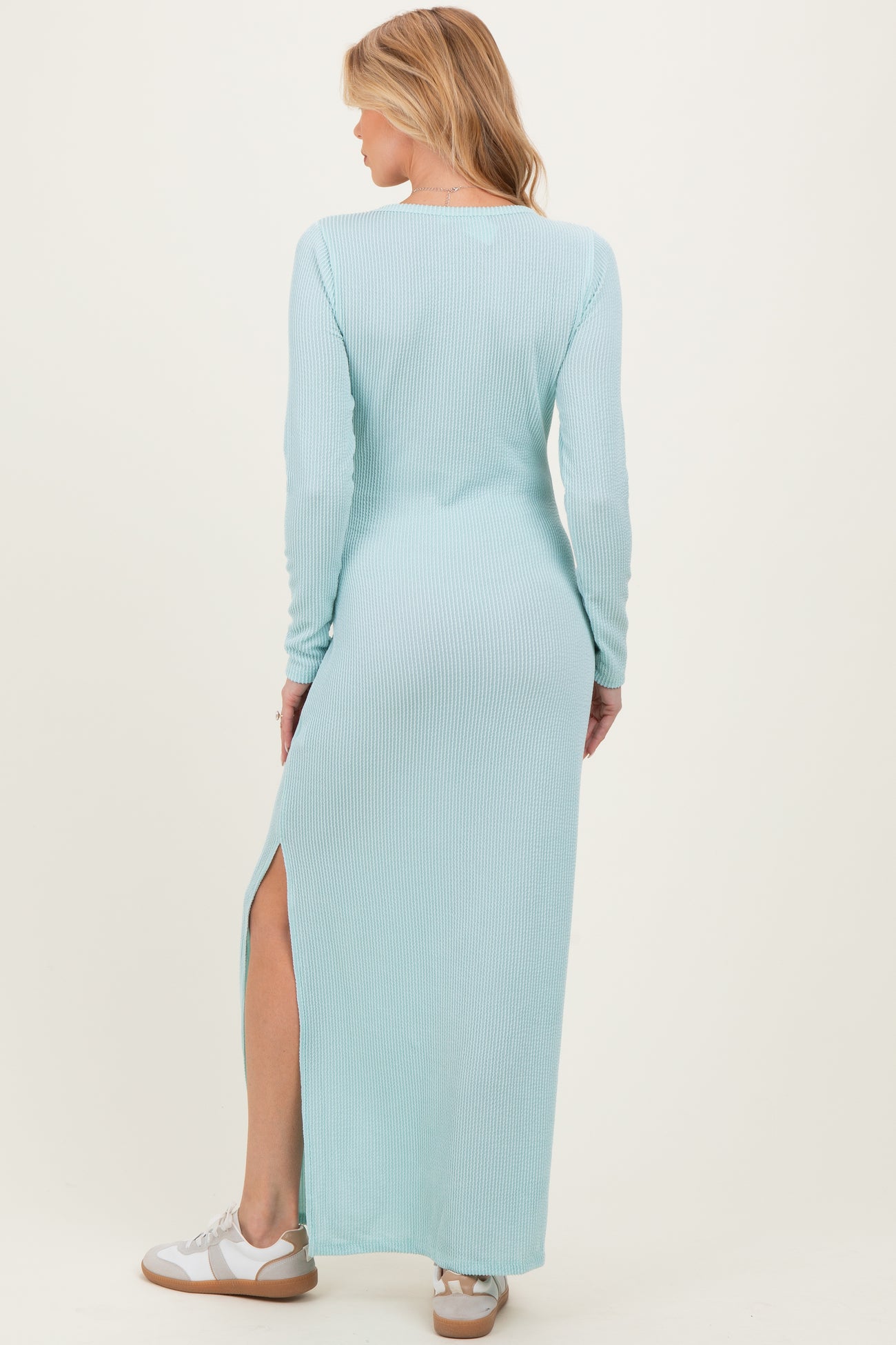 woman wearing a light blue long sleeve ribbed maternity maxi dress with a side slit