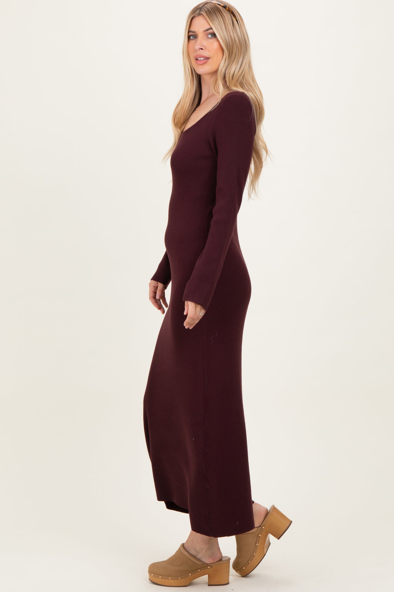 woman wearing a burgundy ribbed maxi dress with a side slit and long sleeves