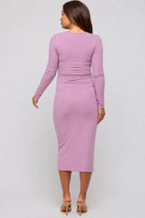 woman wearing a long sleeve mauve maternity dress with a fitted silhouette and ribbed texture, showcasing a baby bump.
