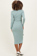 woman wearing a mint green long sleeve maternity dress, view from the back with a fitted silhouette
