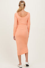 woman wearing a light orange long sleeve maternity dress with a fitted silhouette and midi length from the back