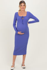 woman wearing a purple ribbed maternity dress with a tie detail, showcasing her baby bump