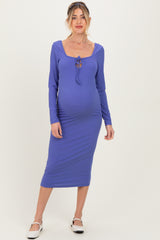 woman wearing a purple long sleeve maternity dress with a square neckline and tie detail, highlighting her baby bump
