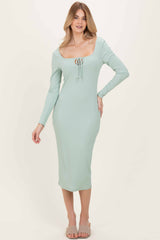 woman wearing a mint green ribbed midi dress with a scoop neckline and long sleeves, standing and smiling