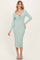 woman wearing a mint green ribbed midi dress with a scoop neckline and long sleeves, standing and smiling