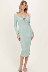 woman wearing a mint green ribbed midi dress with long sleeves and a tied front detail
