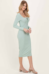woman wearing a light green ribbed midi dress with long sleeves and a scoop neckline, styled with slip-on mules