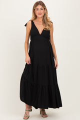 woman wearing a black striped maternity maxi dress with tiered ruffle detail and adjustable tie straps, showing baby bump